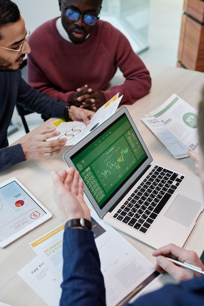 A multicultural team engaged in a collaborative meeting with a laptop and documents in a modern office setting.